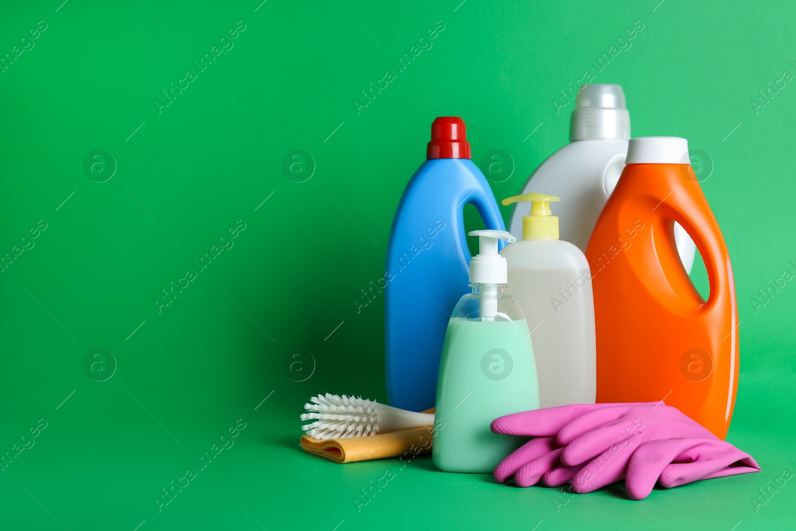 Photo of Different cleaning supplies and tools on green background, space for text