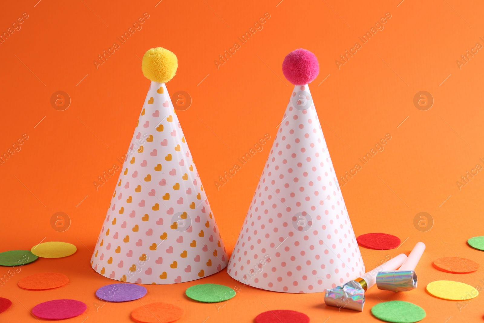 Photo of Party hats and other bright decor elements on orange background