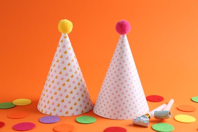 Photo of Party hats and other bright decor elements on orange background