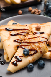 Delicious thin pancakes with chocolate, blueberries and nuts on plate