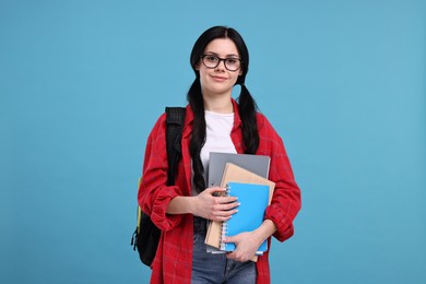 Photo of Student with notebooks, folder and backpack on light blue background