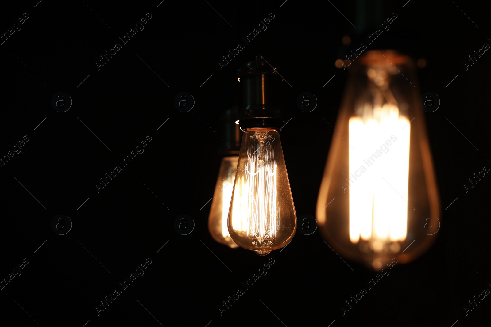 Photo of Edison light bulbs on black background, space for text