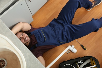 Male plumber repairing kitchen sink, top view