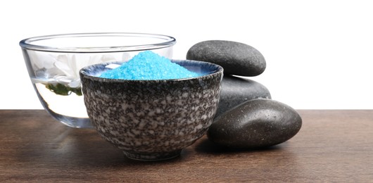 Photo of Light blue sea salt in bowl, spa stones and flowers on wooden table against white background