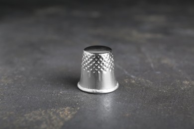 Photo of Silver thimble on grey table. Sewing accessory
