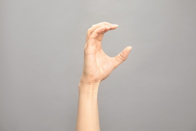 Photo of Woman showing C letter on grey background, closeup. Sign language