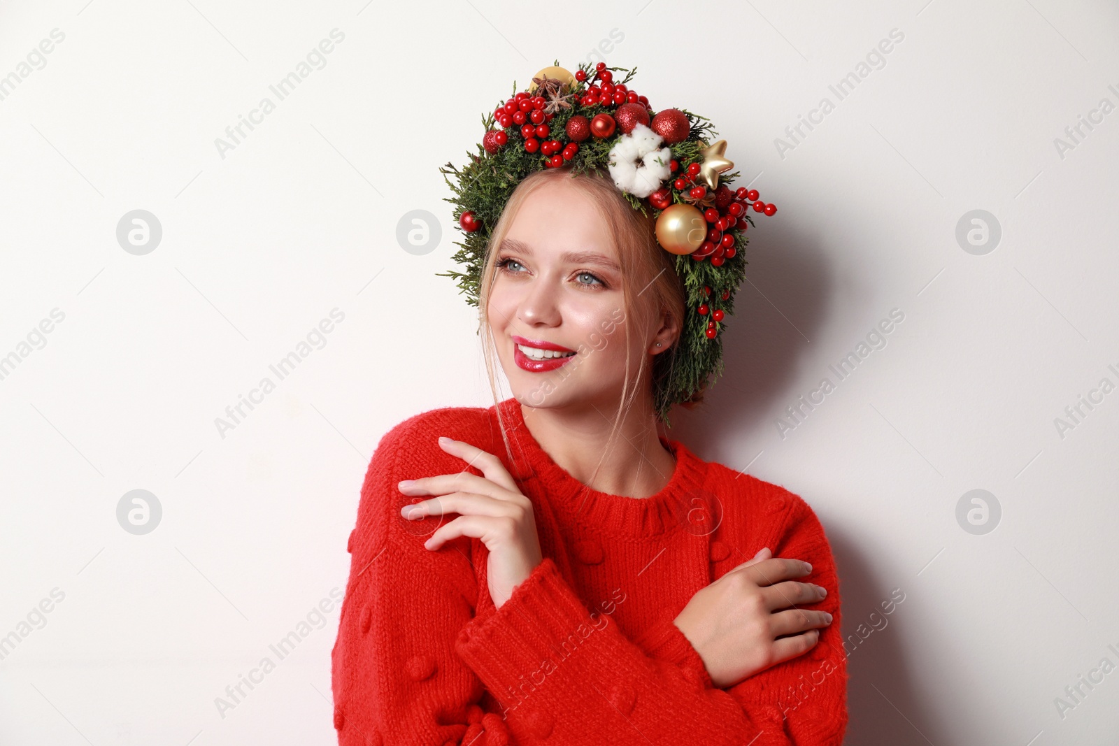 Photo of Beautiful young woman wearing Christmas wreath on white background