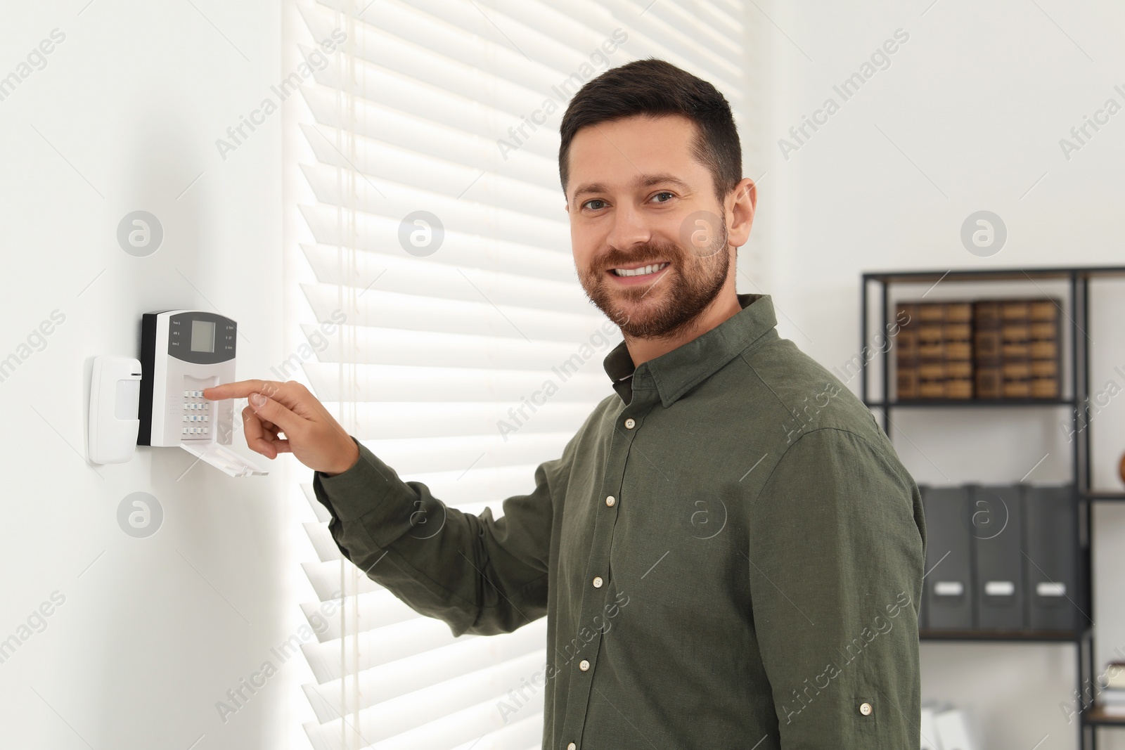 Photo of Man entering code on home security system indoors