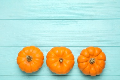 Ripe orange pumpkins on light blue wooden table, flat lay. Space for text