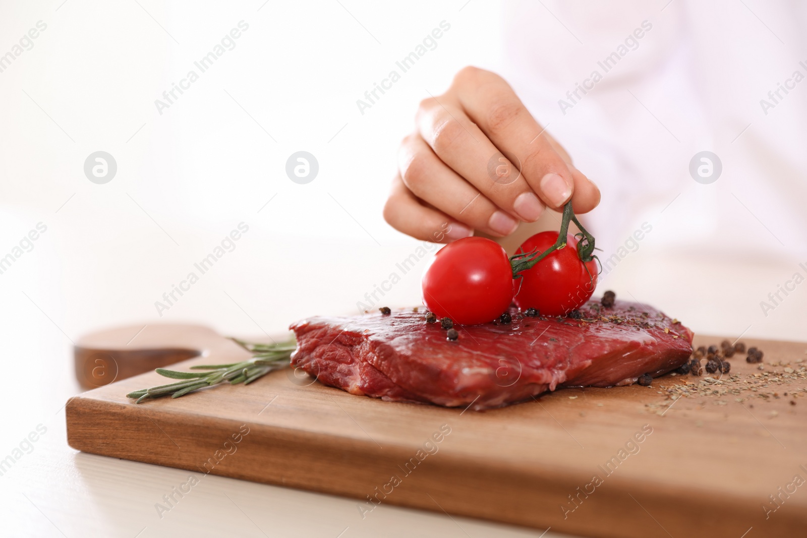Photo of Professional female chef cooking meat on table in kitchen, closeup