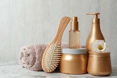 Different hair products, towel and brush on white marble table