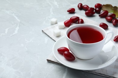 Photo of Cup of fresh dogwood tea and berries on light grey table. Space for text