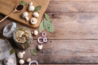 Photo of Glass jar of pickled mushrooms on wooden table, flat lay. Space for text