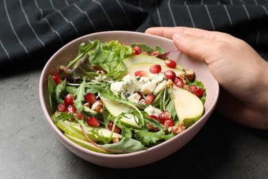Photo of Woman with tasty pear salad at grey table, closeup