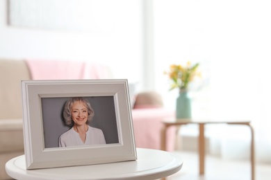 Framed portrait of senior woman on table indoors. Space for text