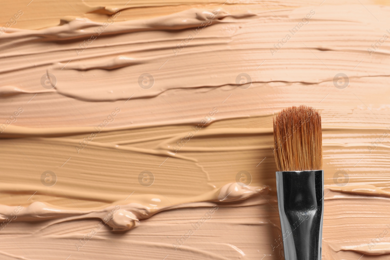 Photo of Samples of skin foundation and makeup brush, top view