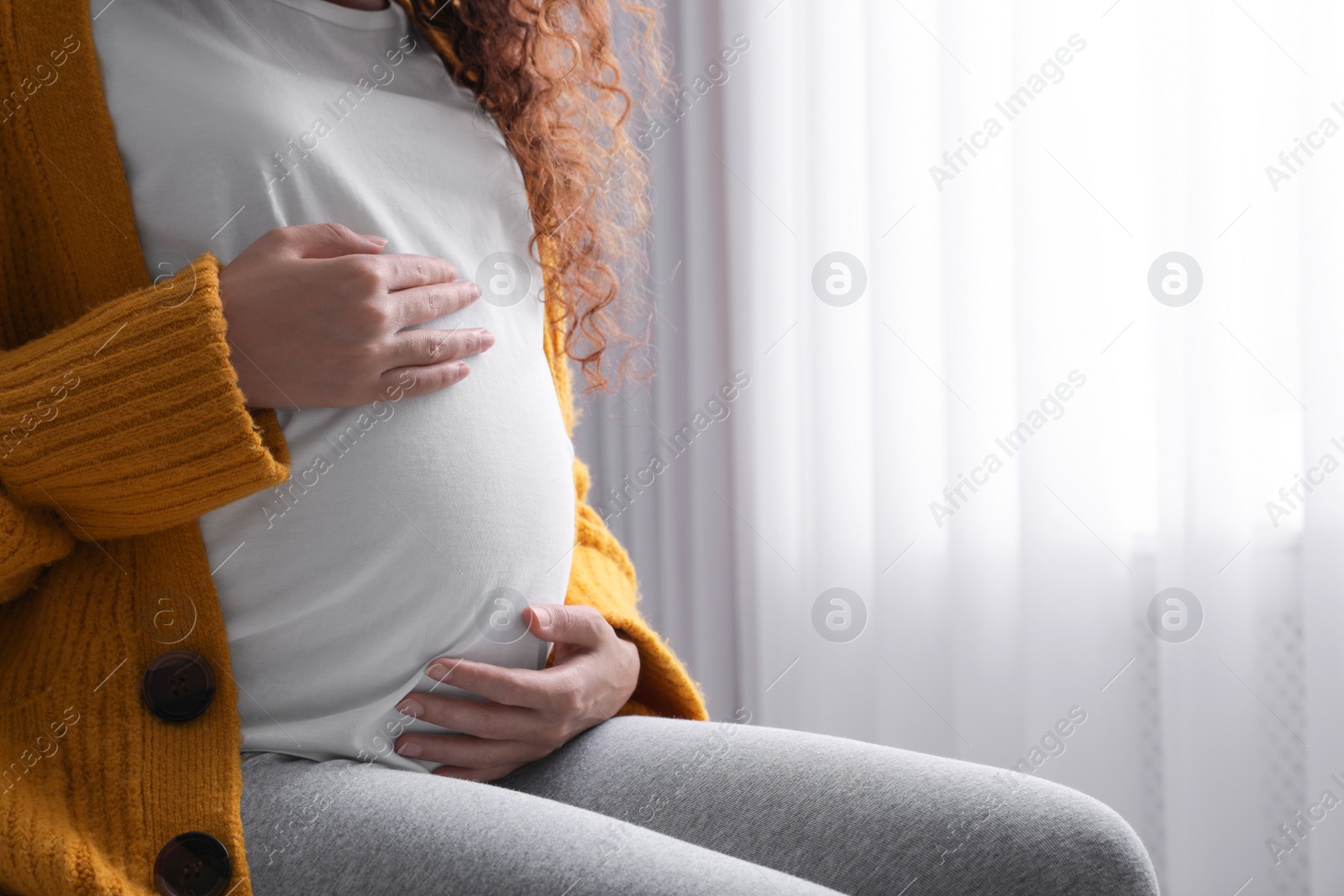 Photo of Pregnant African-American woman at home, closeup. Space for text