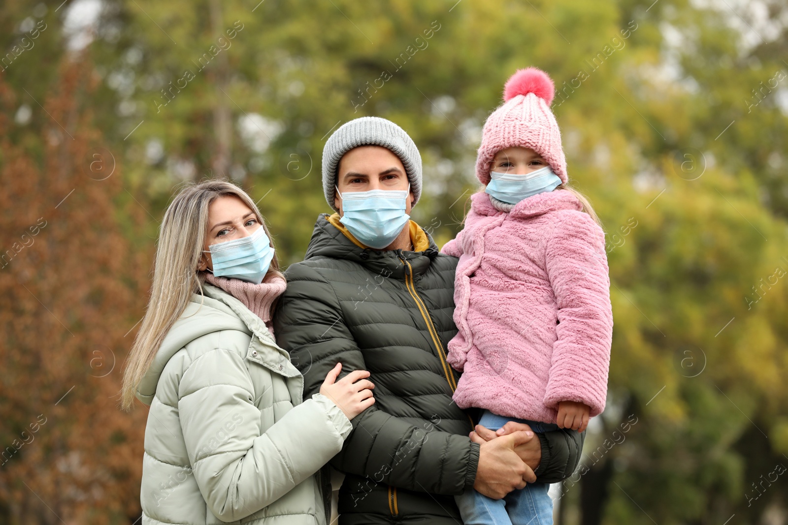 Photo of Family in medical masks outdoors on autumn day. Protective measures during coronavirus quarantine