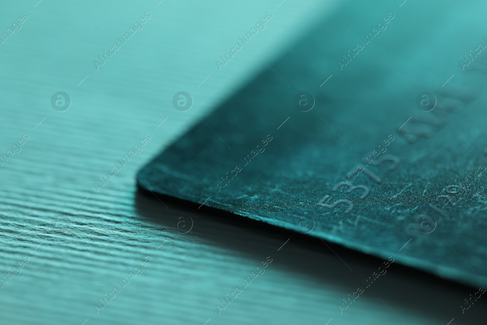 Photo of One credit card on turquoise background, closeup