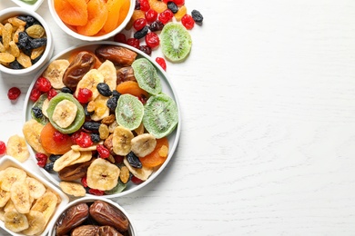 Photo of Bowls of different dried fruits on wooden background, top view with space for text. Healthy lifestyle