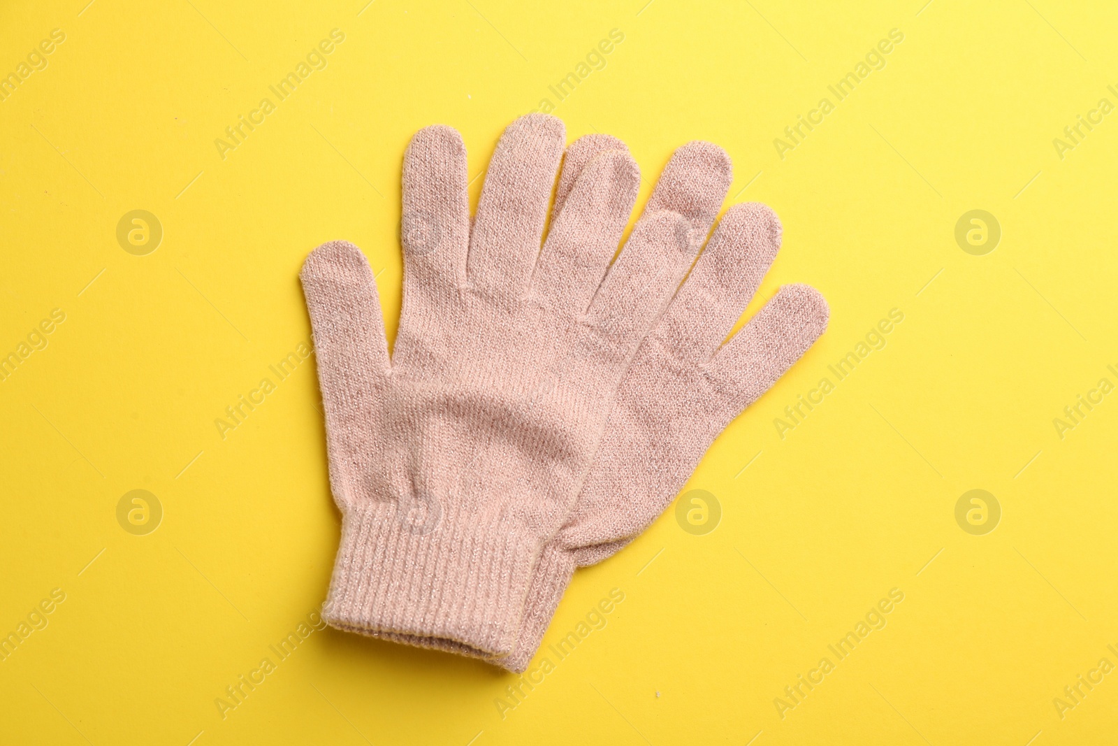 Photo of Pair of stylish woolen gloves on yellow background, flat lay