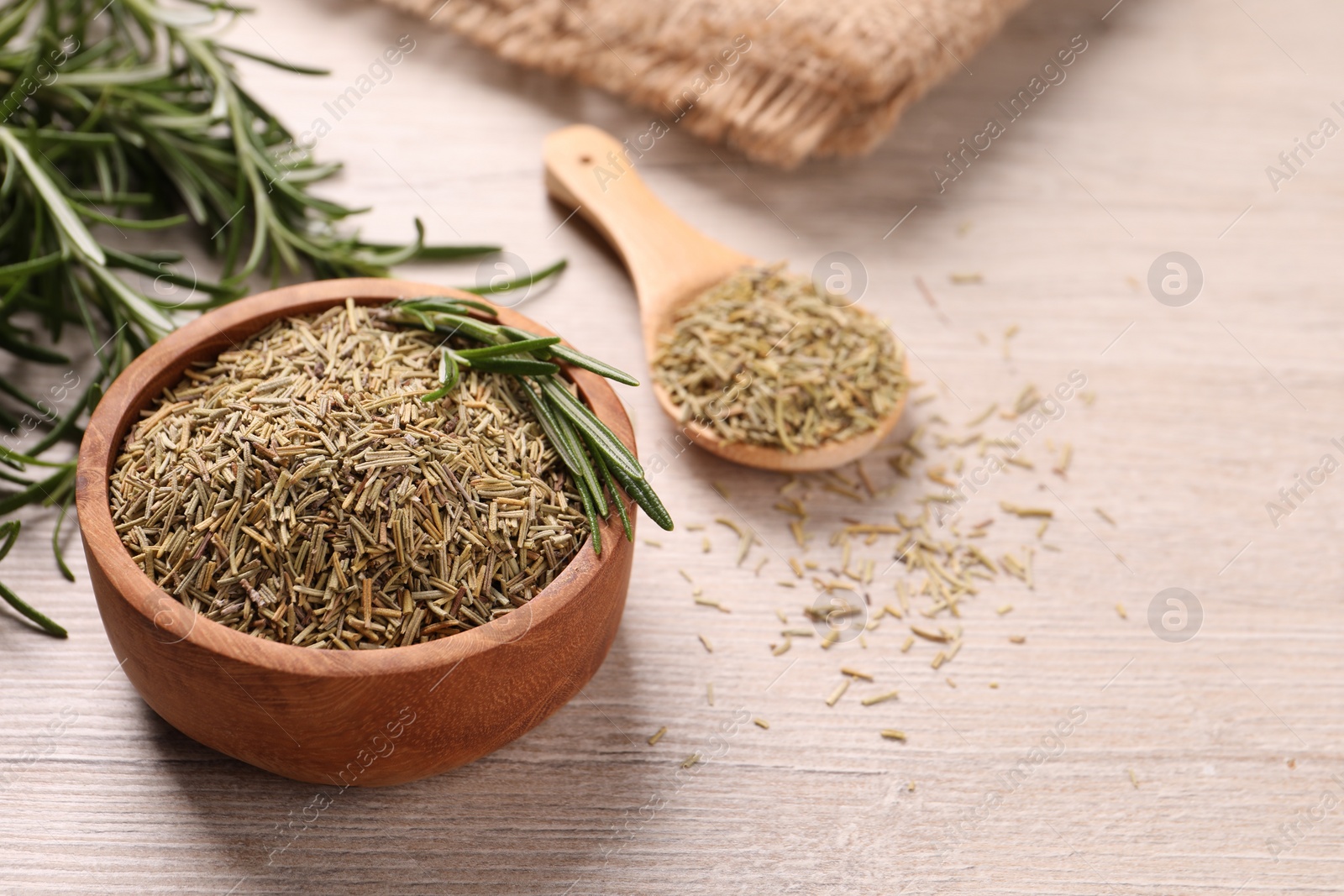 Photo of Bowl with dry and fresh rosemary on white wooden table, closeup. Space for text