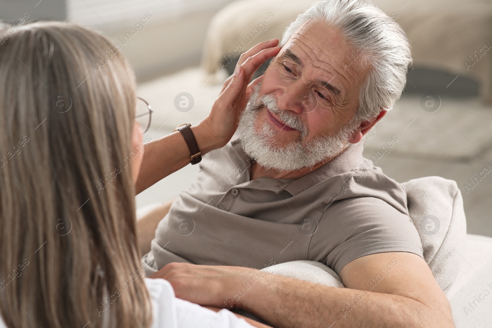 Photo of Affectionate senior couple relaxing on sofa at home