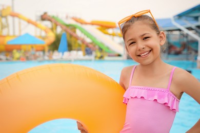 Photo of Cute little girl with inflatable ring near pool in water park