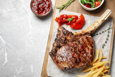 Delicious grilled ribeye steak served on light grey marble table, flat lay. Space for text