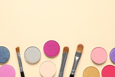 Photo of Different beautiful eye shadows and makeup brushes on beige background, flat lay. Space for text