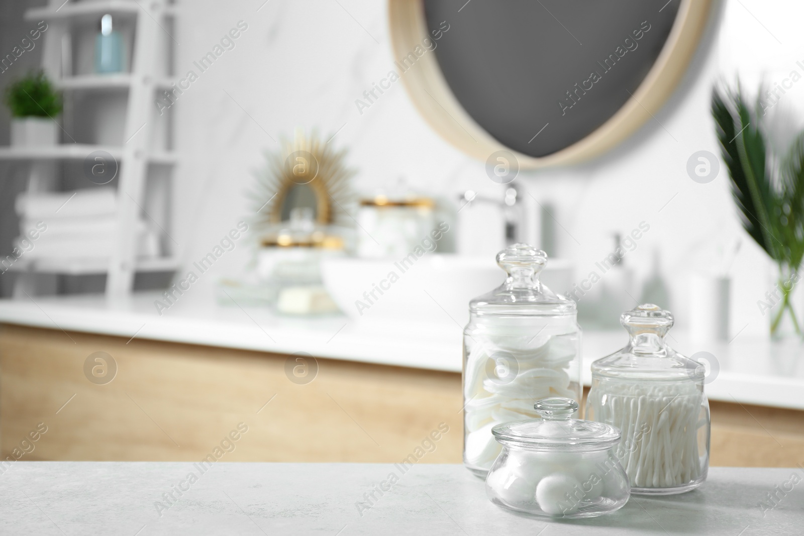 Photo of Cotton balls, swabs and pads on light grey table in bathroom