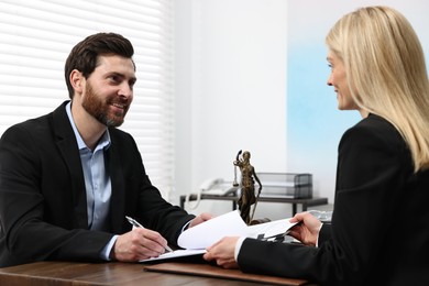 Photo of Man signing document at table in lawyer's office