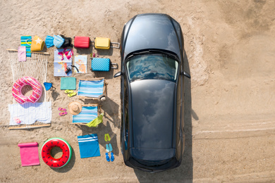 Car and beach accessories on sand, aerial view. Summer trip
