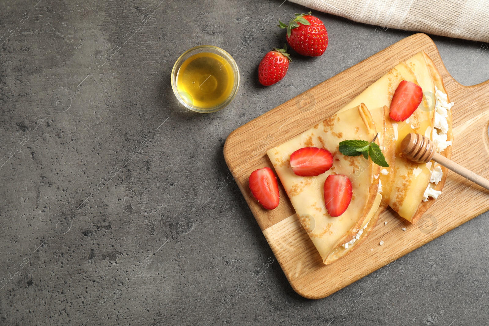 Photo of Delicious thin pancakes with strawberries, cottage cheese and honey on grey table, flat lay. Space for text