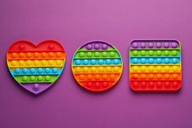 Photo of Rainbow pop it fidget toys on purple background, flat lay