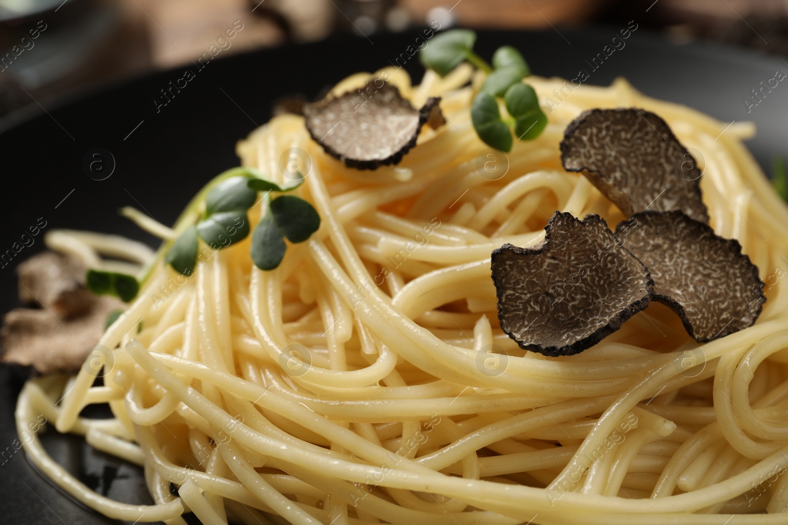 Photo of Tasty spaghetti with truffle on black plate, closeup