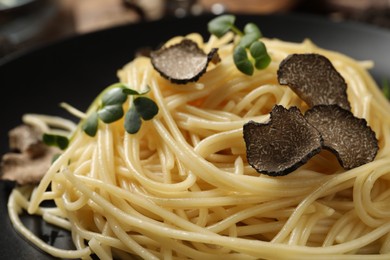 Tasty spaghetti with truffle on black plate, closeup