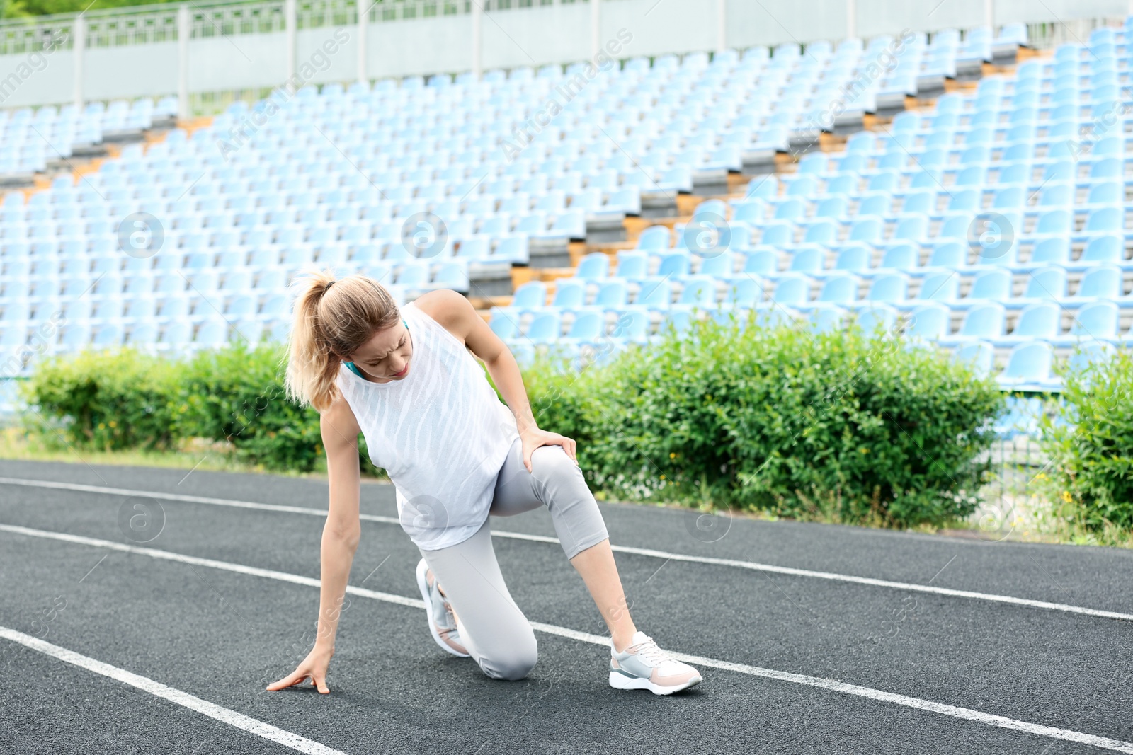 Photo of Woman in sportswear suffering from knee pain at stadium