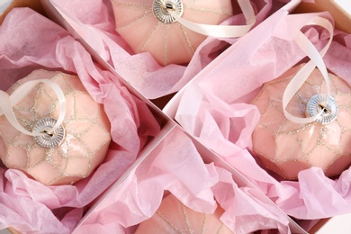 Photo of Beautiful Christmas baubles wrapped in pink paper inside box, top view
