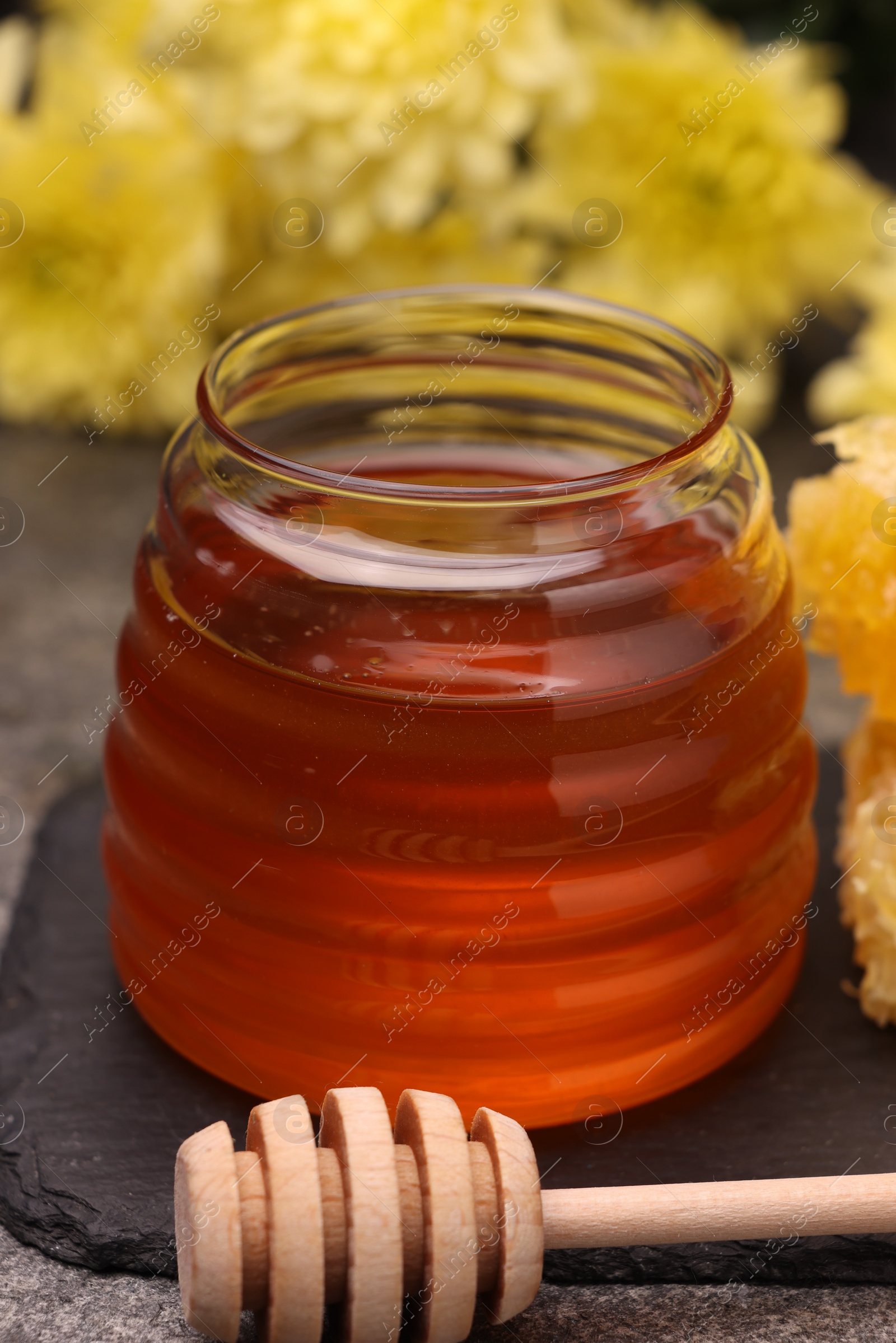 Photo of Sweet golden honey in jar and dipper on table, closeup
