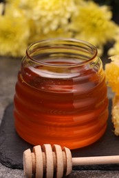 Sweet golden honey in jar and dipper on table, closeup