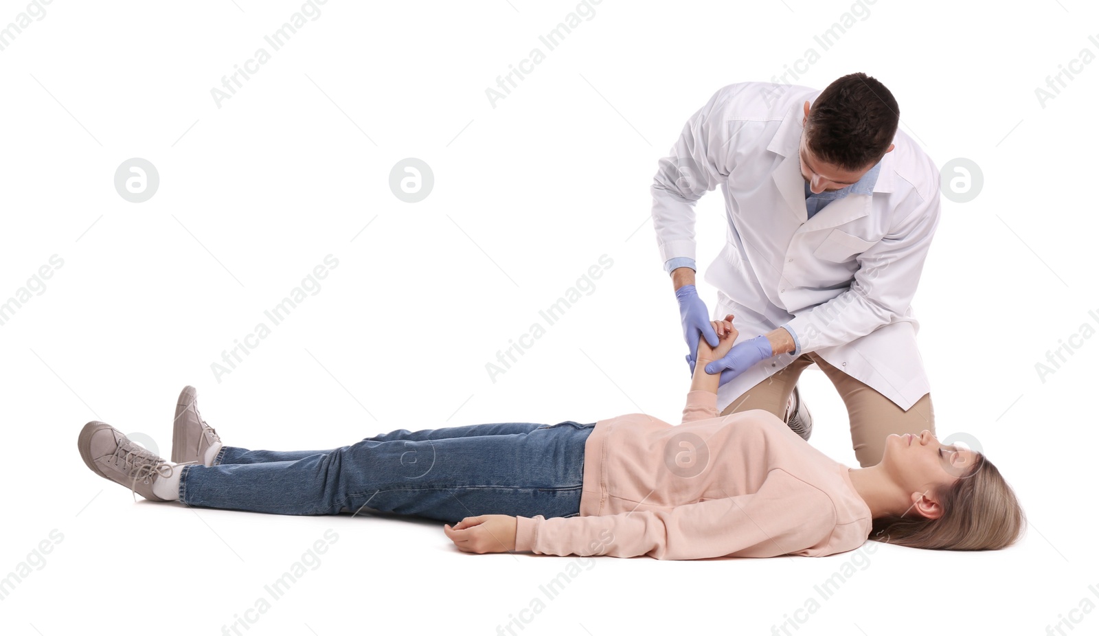 Photo of Doctor in uniform performing first aid on unconscious woman against white background