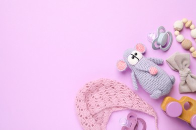 Photo of Flat lay composition with pacifiers and other baby stuff on violet background. Space for text
