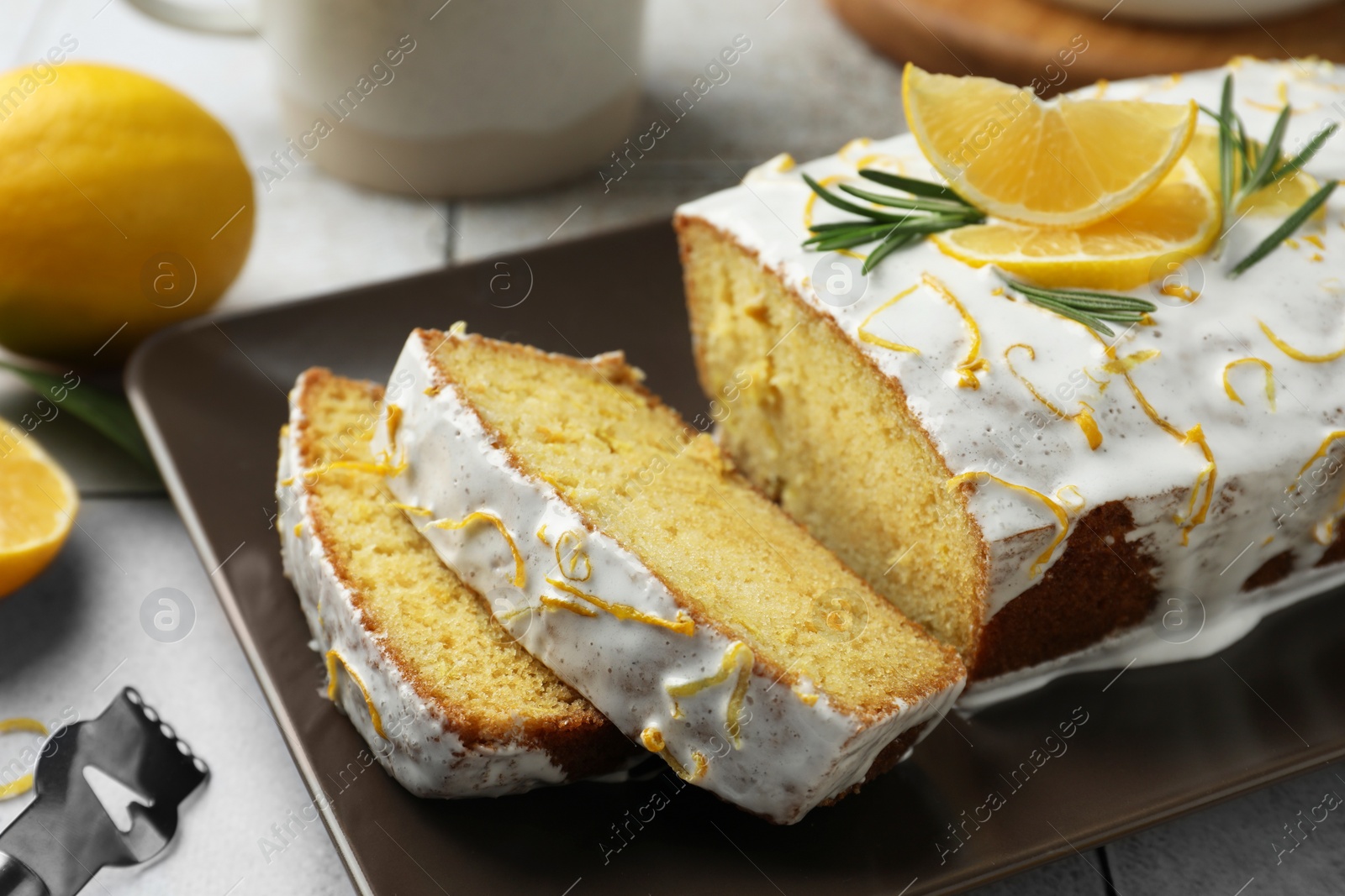 Photo of Tasty lemon cake with glaze and citrus fruits on table, closeup