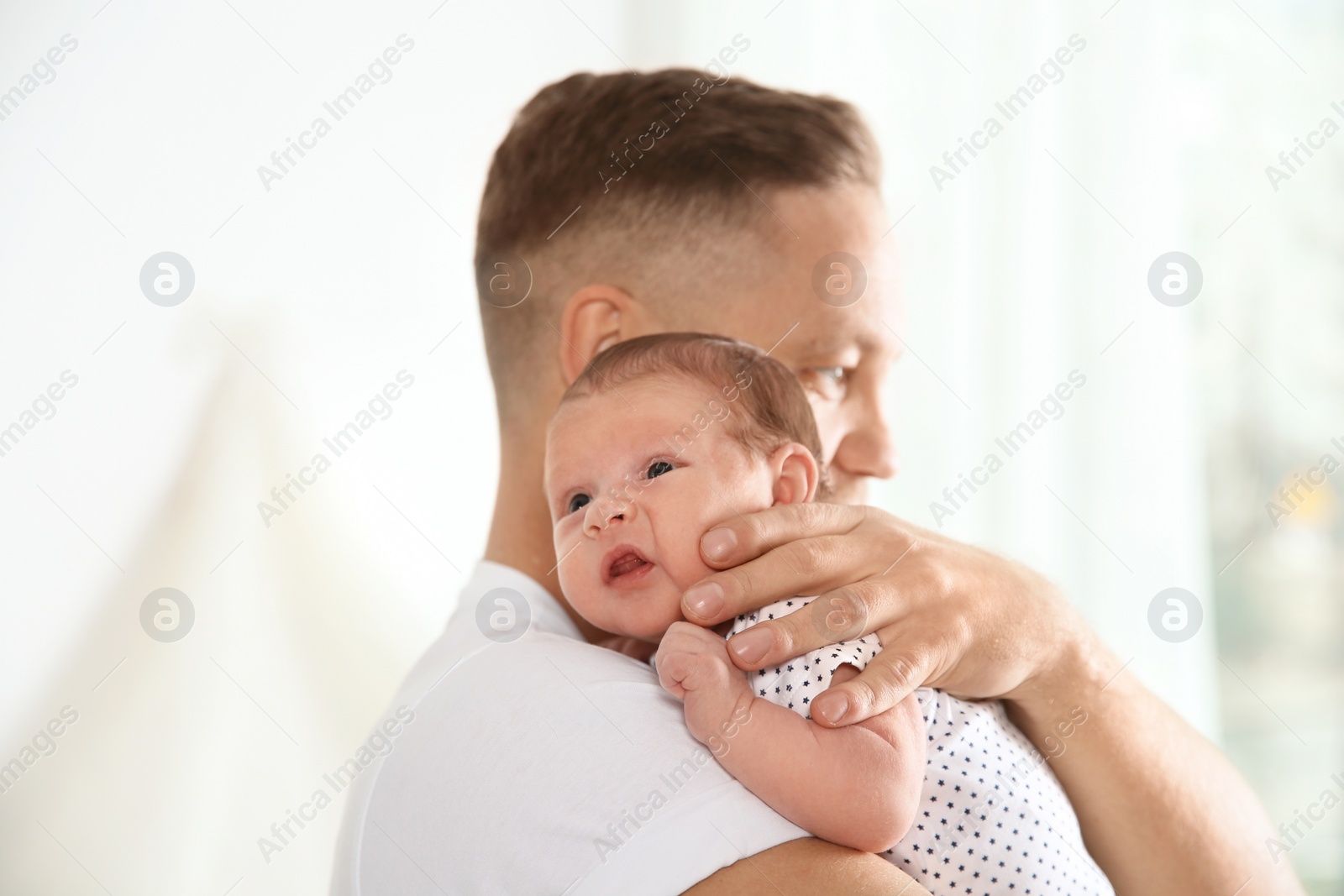 Photo of Man with his newborn baby on light background