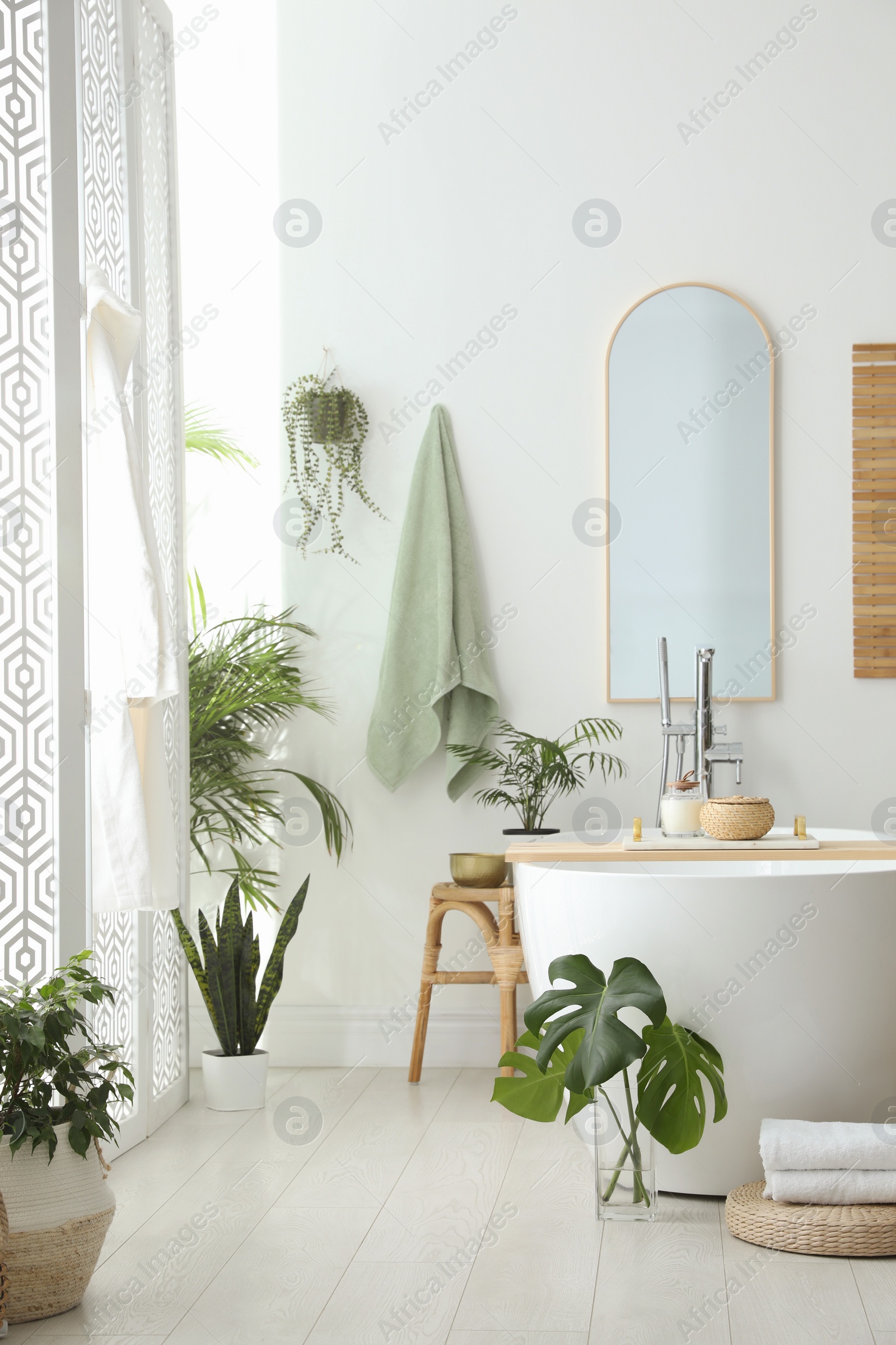 Photo of Stylish bathroom interior with modern tub, houseplants and beautiful decor. Home design