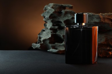 Luxury men`s perfume in bottle on grey table against brown background, space for text