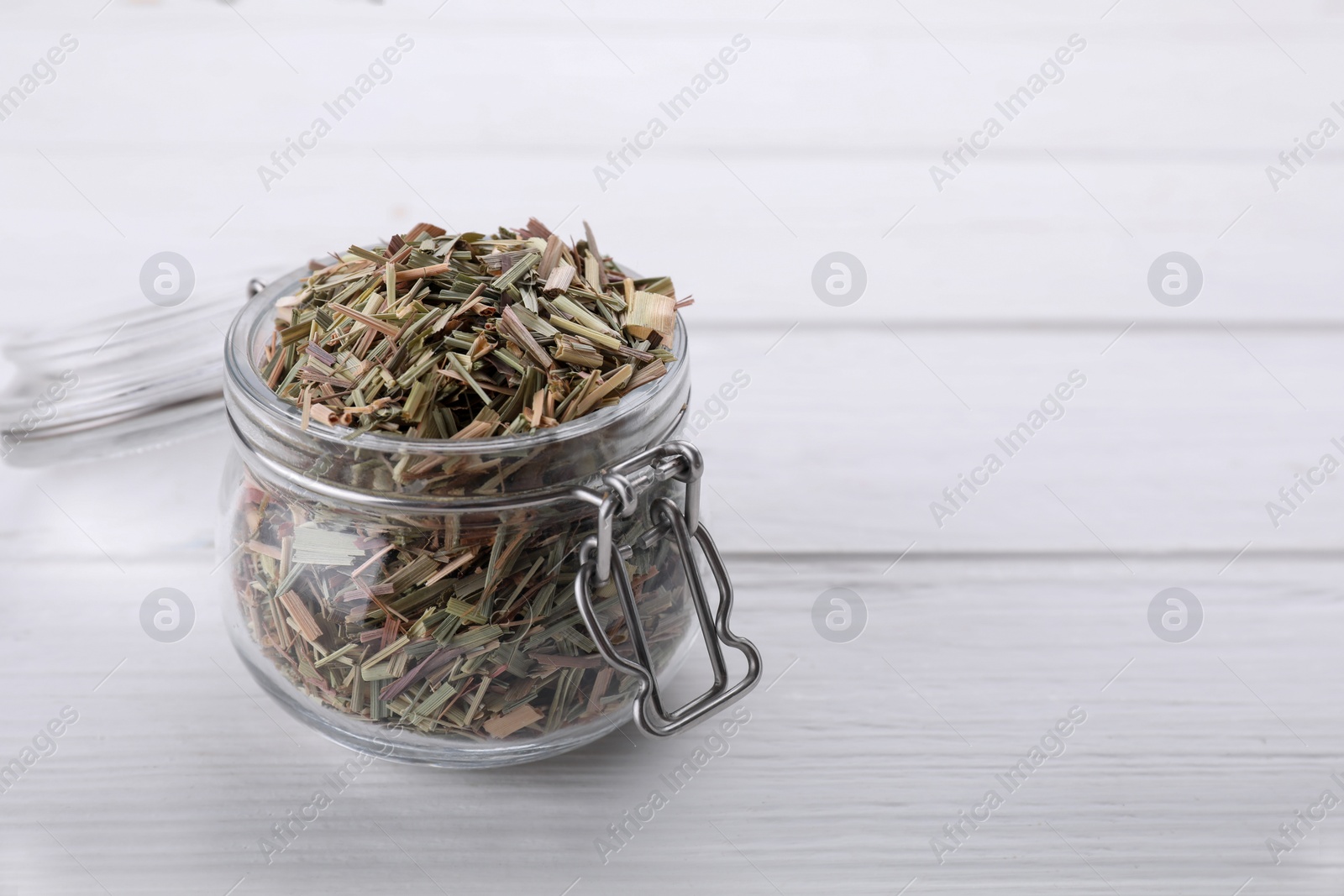 Photo of Glass jar with aromatic dried lemongrass on white wooden table. Space for text