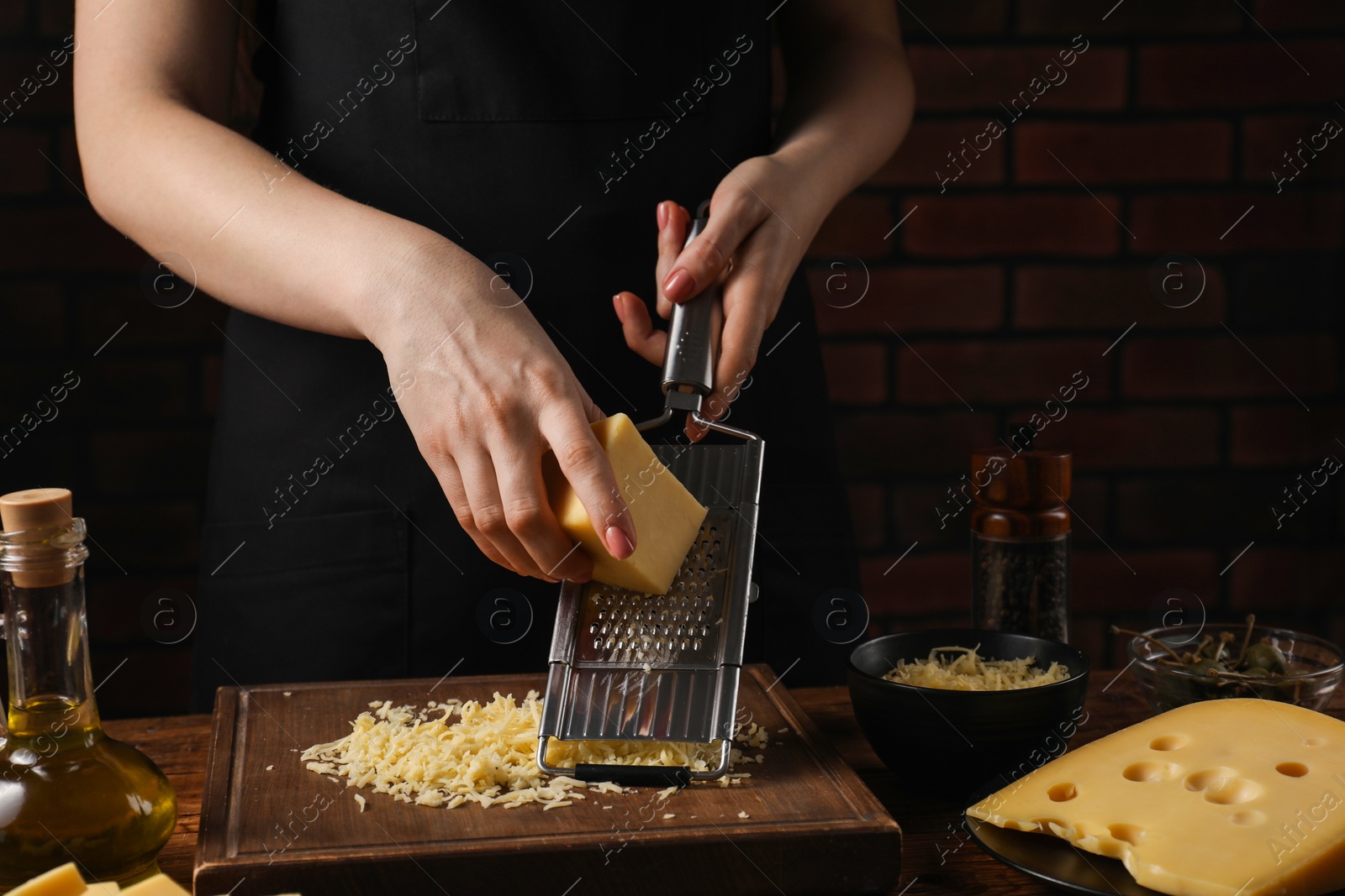 Photo of Woman grating cheese at wooden table, closeup