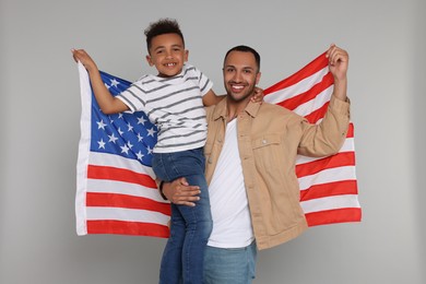 Photo of 4th of July - Independence Day of USA. Happy man and his son with American flag on light grey background